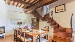 A dining area with a wooden table, chairs, and a staircase with a metal railing.