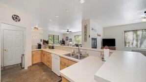 A modern kitchen with white countertops, a dishwasher, and a large window. - Sequoia Pines - 411 Sequoia Circle (Plumas Eureka)