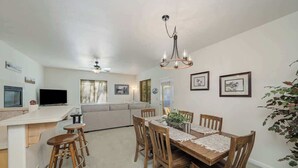 A dining area with a wooden table, four chairs, and a chandelier. There is a bar area with stools and a television. - Sequoia Pines - 411 Sequoia Circle (Plumas Eureka)