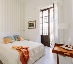 Une chambre bien rangée, avec un lit, des tables de chevet, un bureau et une fenêtre avec des rideaux.