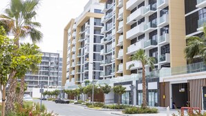 A modern multi-story building with balconies, a street in front, and palm trees. - Nasma Luxury Stays - Riviera 10 (Dubai)