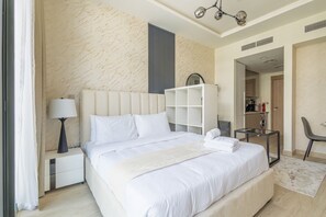 A modern hotel room with a large bed, a bedside table with a lamp, a wardrobe, and a view into the kitchen area. - Nasma Luxury Stays - Riviera 10 (Dubai)