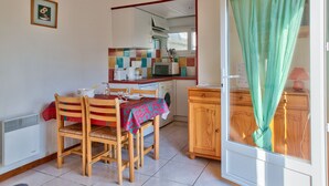 A kitchen with a dining table, chairs, a microwave, and a washing machine. - House for 2 - 100 m from La Joie beach (Penmarch)