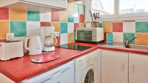 A kitchen with a red countertop, a coffee maker, a toaster, a washing machine, and a colorful tiled backsplash. - House for 2 - 100 m from La Joie beach (Penmarch)