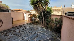 Ein Innenhof mit Steinpflasterung, einer Palme und einem Gebäude mit Ziegeldach.