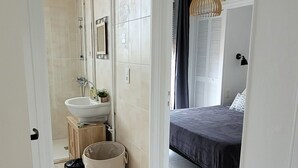 Ein Schlafzimmer mit Bett, Nachttisch, einer Hängelampe und einem Fenster mit Vorhängen.
