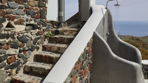 A stone staircase with a white door and a concrete slide leading to a white platform. - El Verano Hideaway Villa (Santorini)