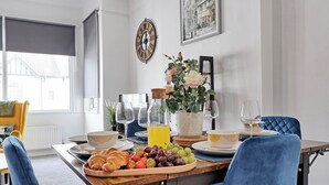 Taula de menjador preparada per esmorzar, amb croissants, raïm i un plat de fruita.