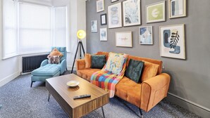 A modern living room with a sofa, armchair, coffee table, and floor lamp.