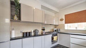 A modern kitchen with white cabinets, a black countertop, a gas stove, and a microwave.