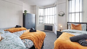 A hotel room with two beds, a wardrobe, a radiator, and a window with blinds.