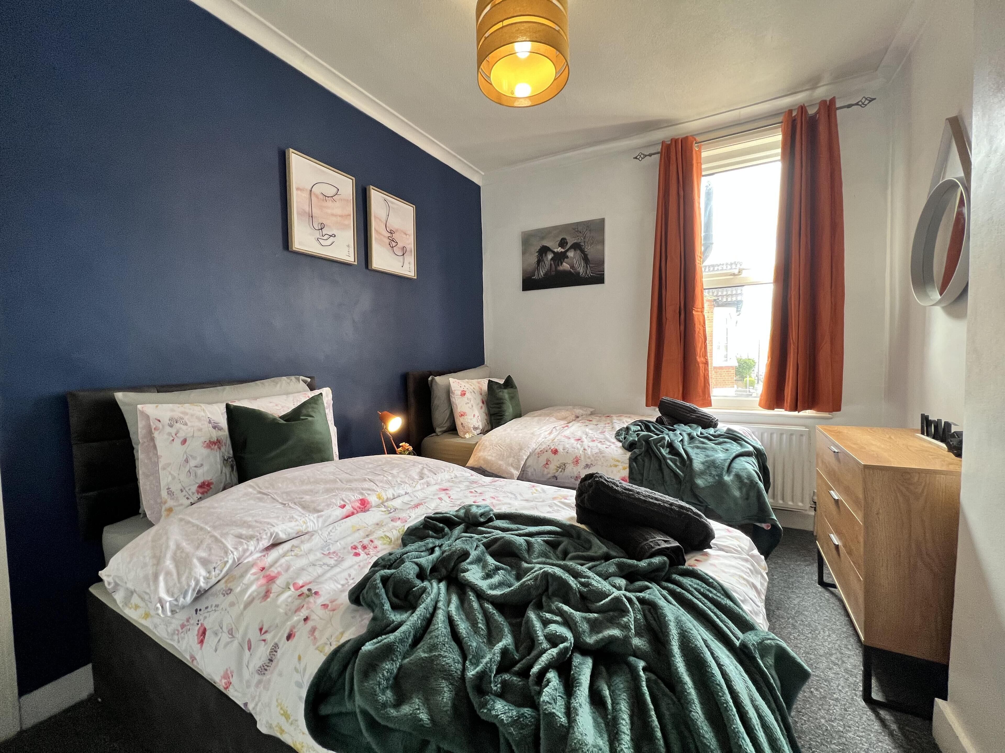 Une chambre avec deux lits, un bureau et une fenêtre avec des rideaux.