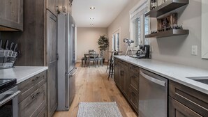A modern kitchen with wooden cabinets, a stainless steel refrigerator, and a built-in dishwasher. - Classy Cabin | Beaches | Grand Mere | Wineries (Stevensville)