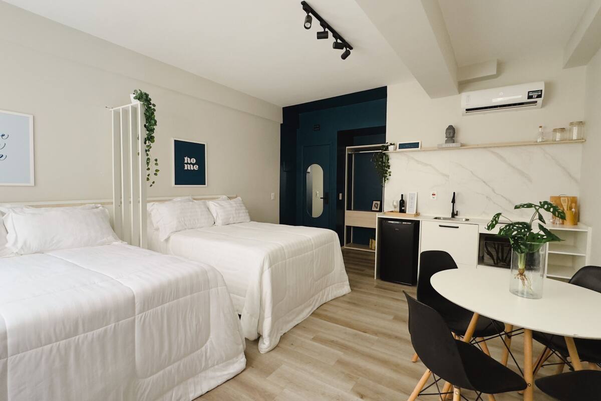 Une chambre d’hôtel moderne avec deux lits simples, un petit coin repas et une kitchenette.