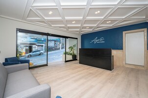 Uma área de recepção moderna com parede de vidro, balcão de atendimento e espaço de espera.