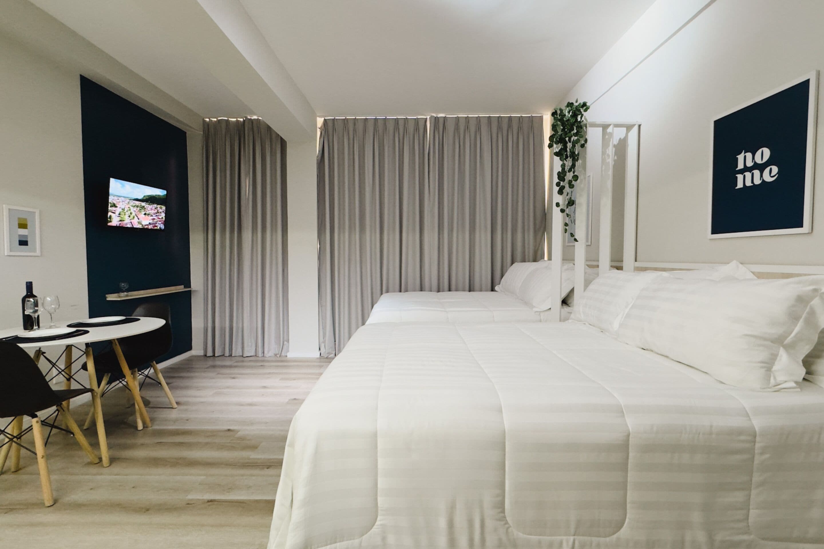 Een moderne hotelkamer met een bed, een bureau met stoel, een televisie en uitzicht op het landschap.