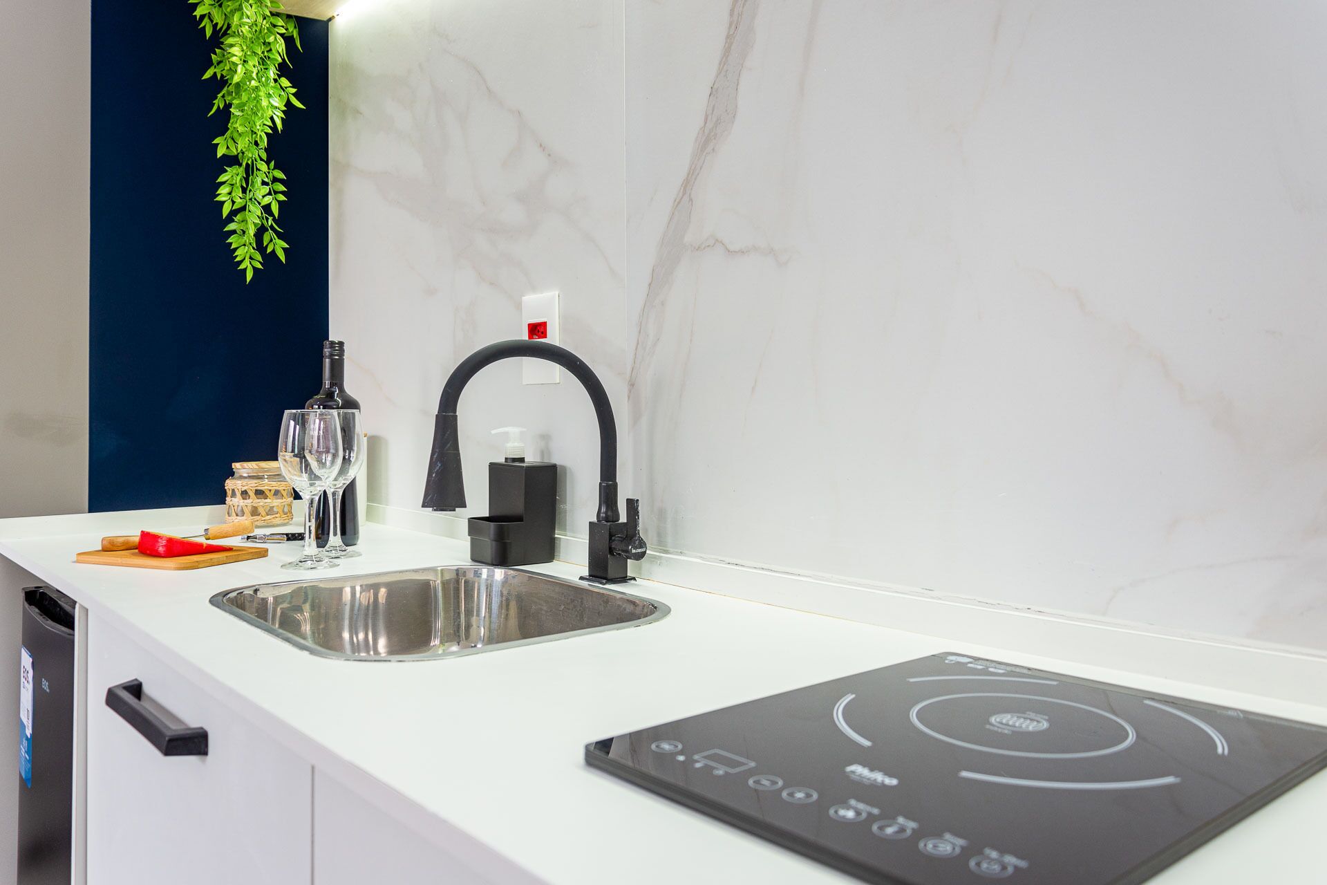 Una cocina moderna con un lavamanos empotrado, un grifo negro y una placa de inducción integrada.