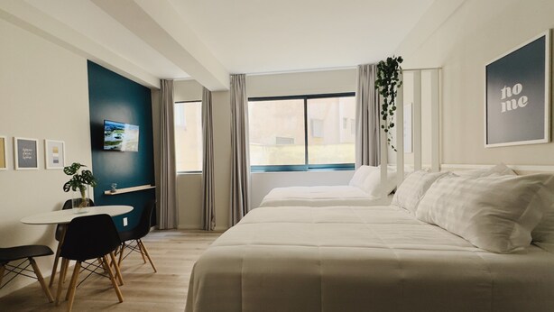 Un dormitorio con una cama grande, un escritorio y una ventana con cortinas.