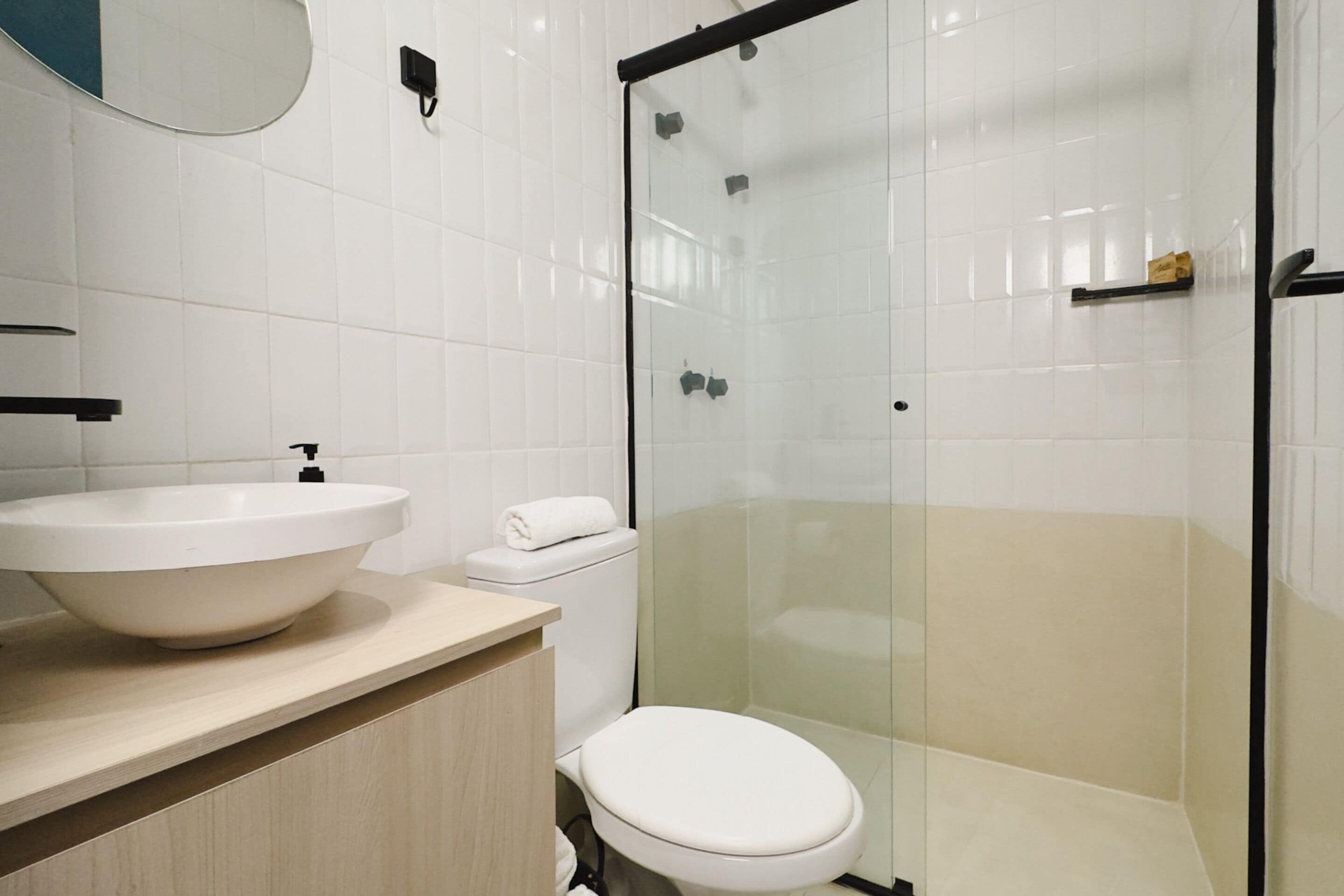 A modern bathroom with a large white sink, a toilet, and a glass-enclosed shower area.