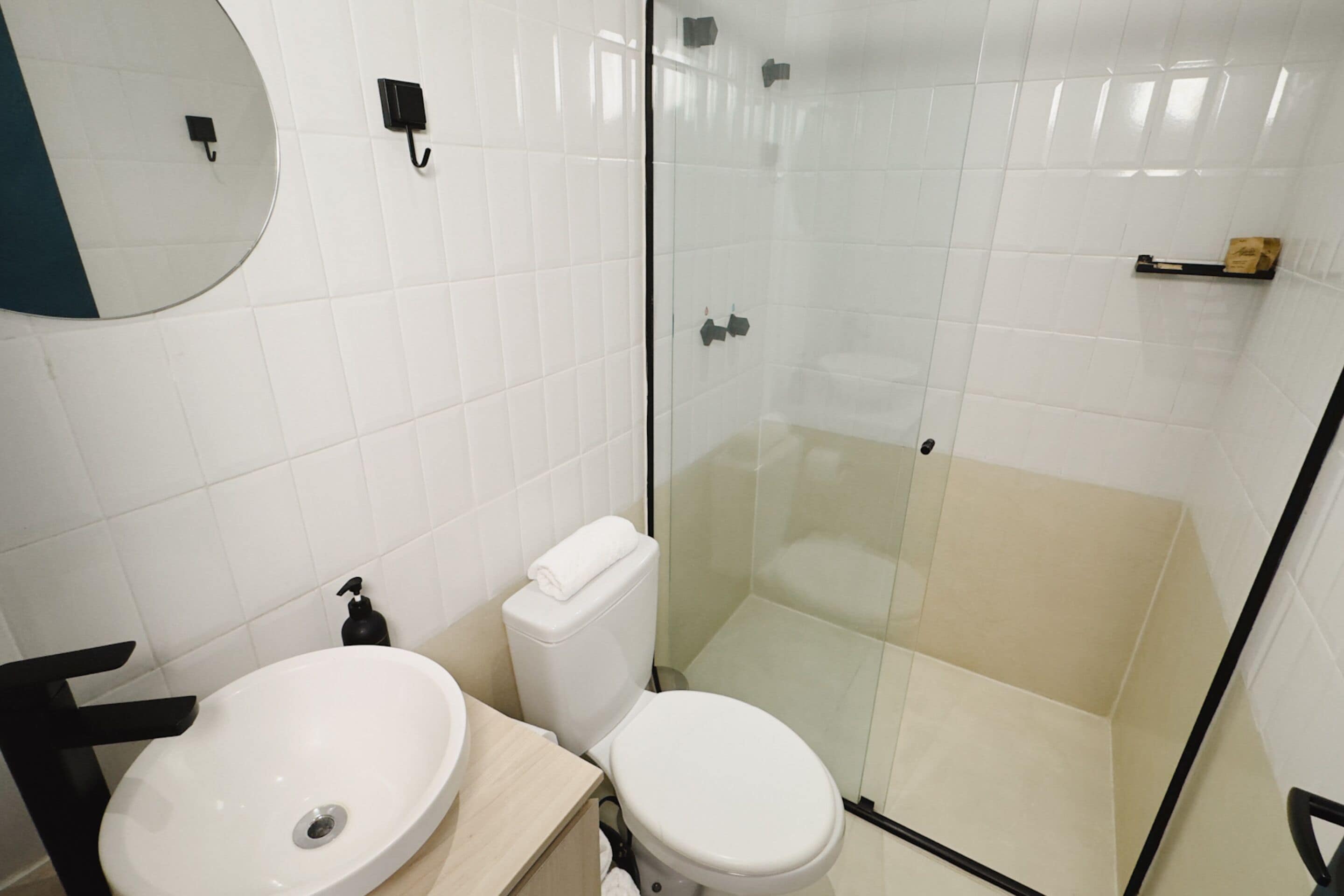 Un baño moderno con lavamanos, inodoro y cabina de ducha de vidrio.