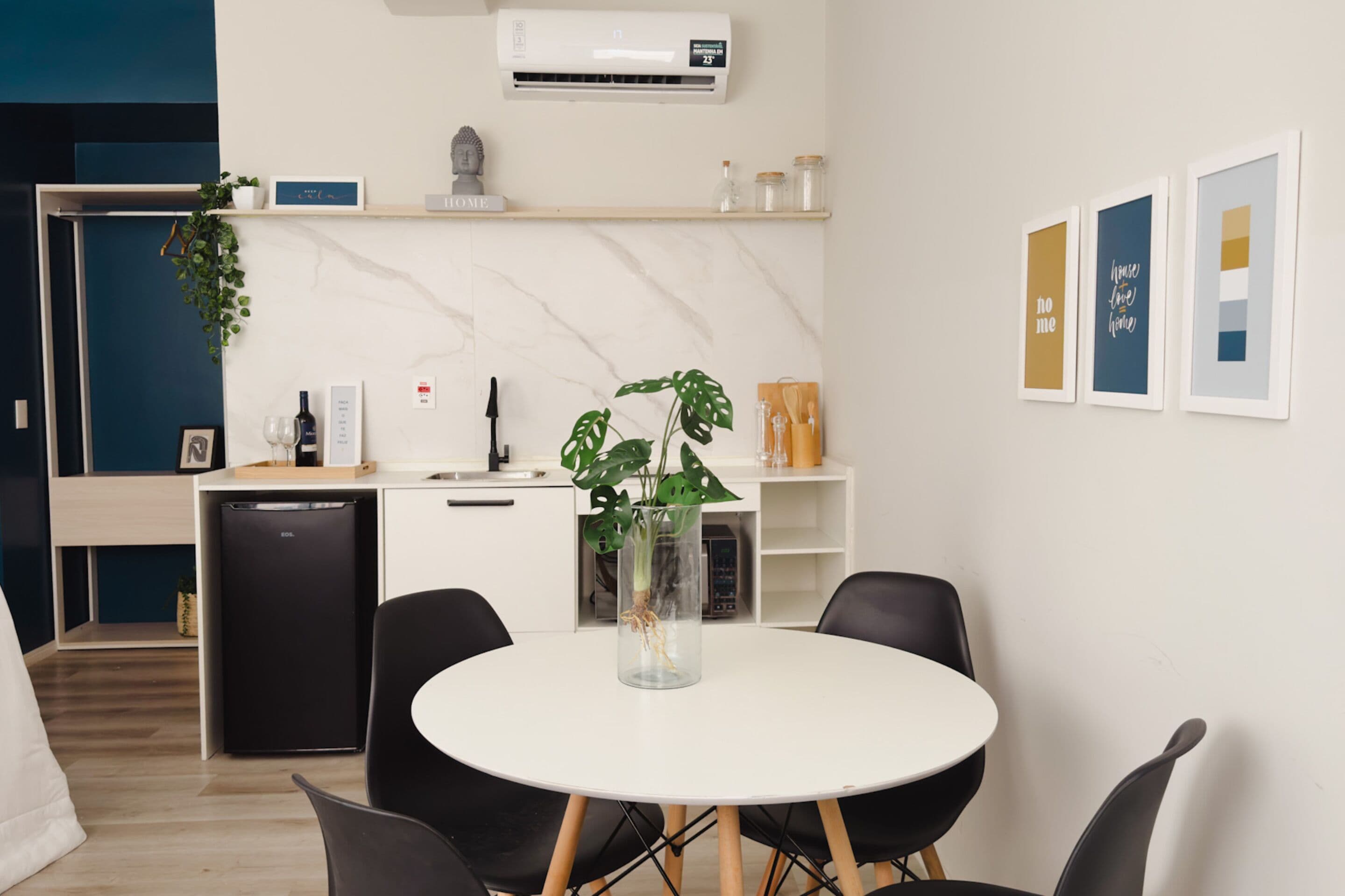 A modern kitchen with a white countertop, black chairs, and a dining table.
