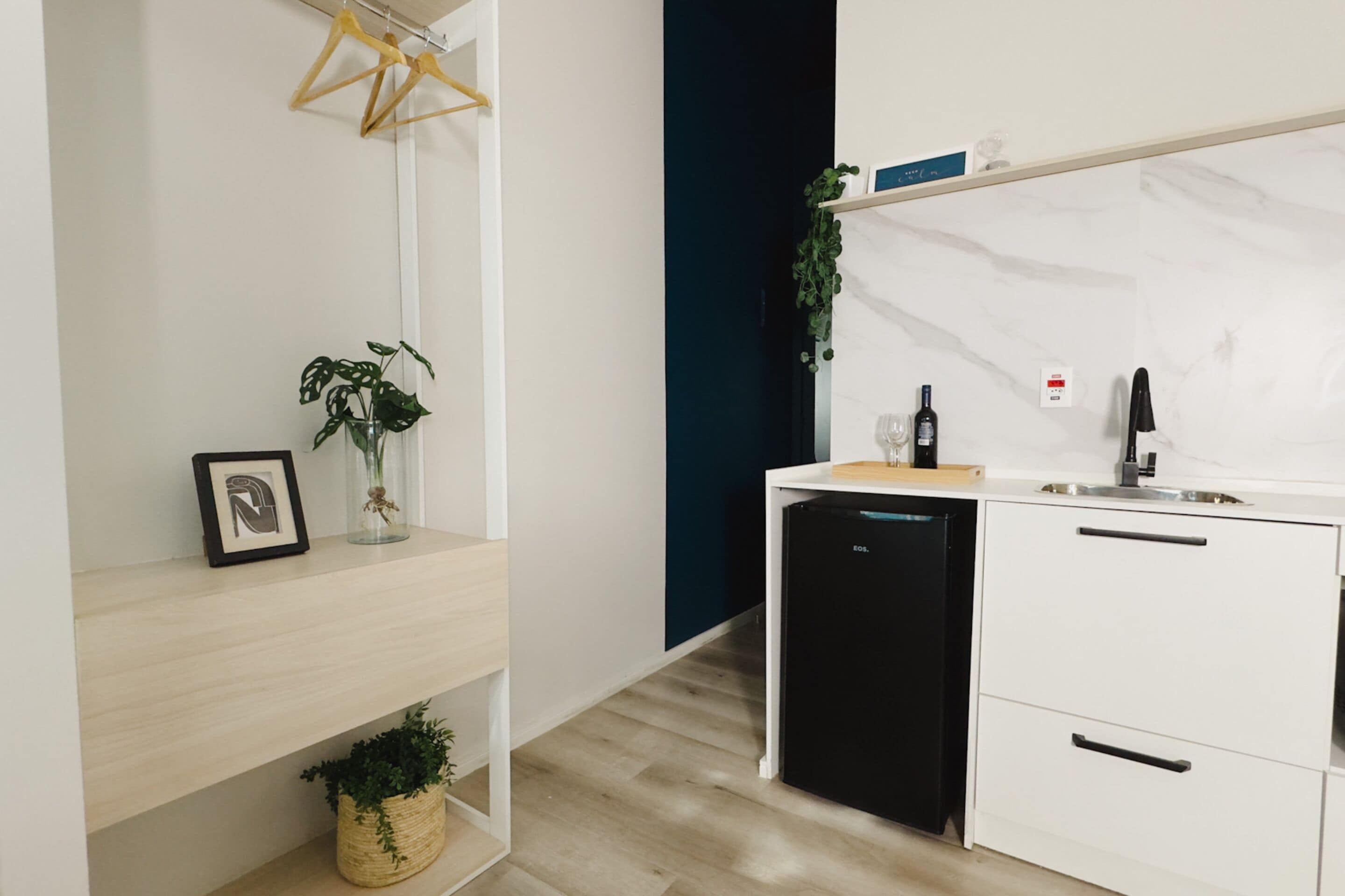 A compact kitchen with a black refrigerator, white cabinets, and a wooden countertop.