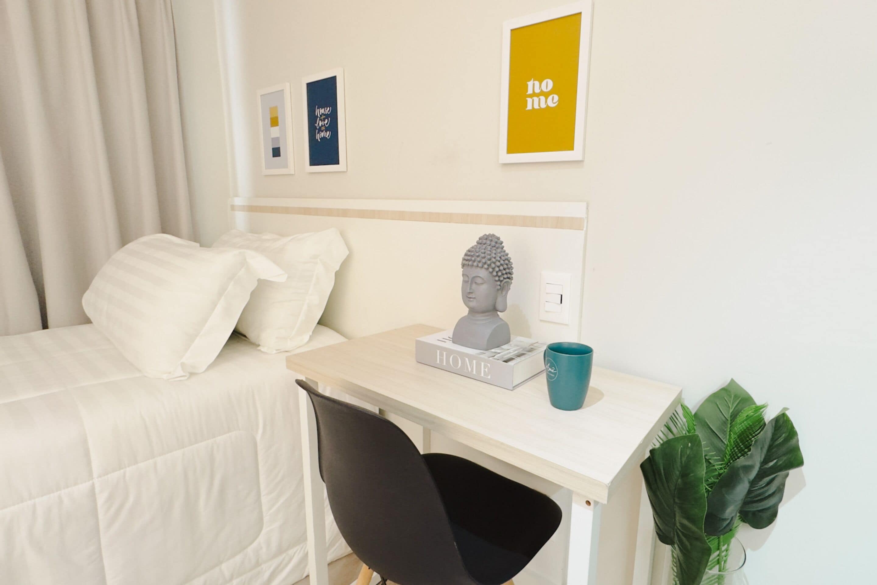 Habitación de hotel con cama, un escritorio con una escultura de busto, una taza y cuadros en la pared.