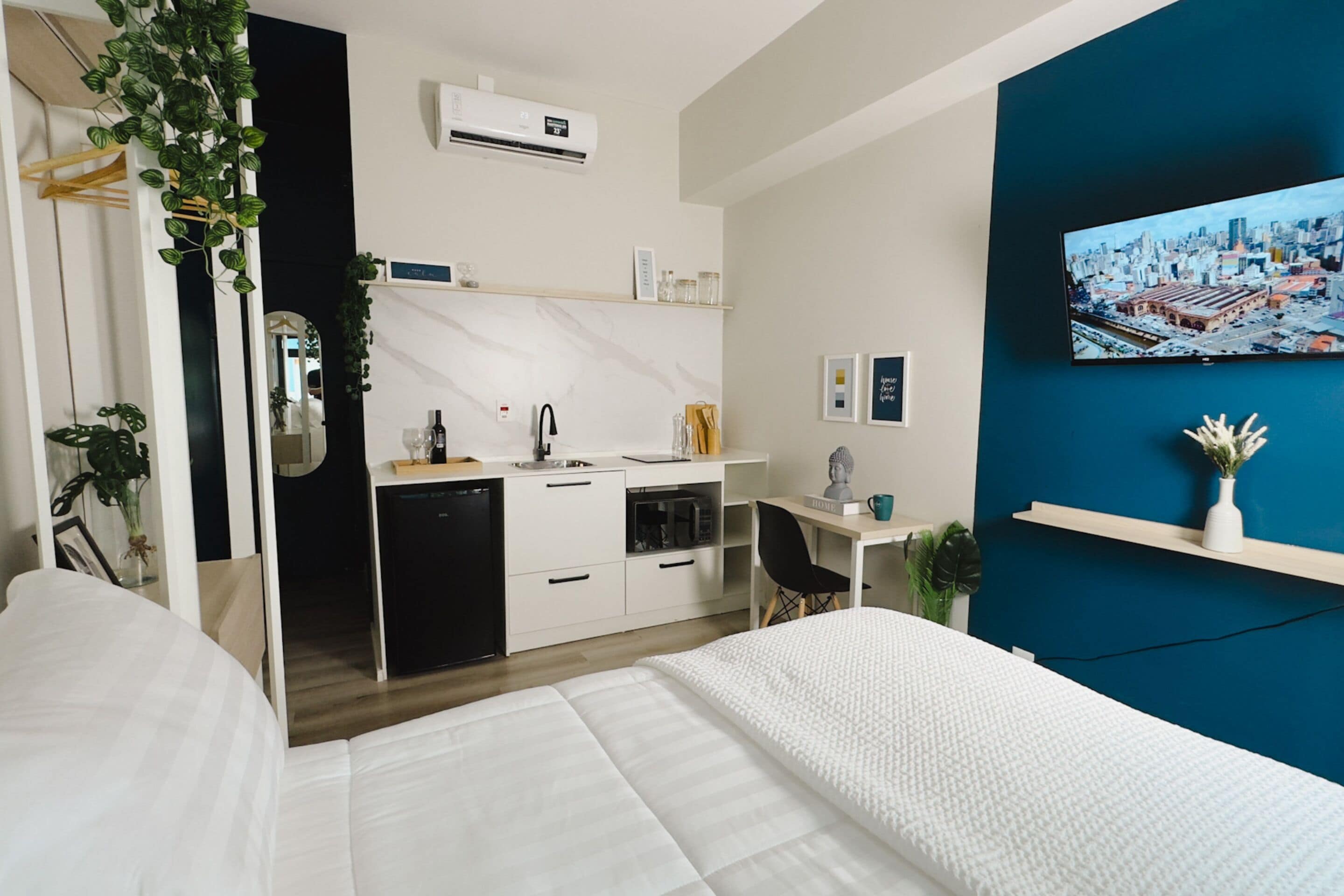 Een moderne hotelkamer met een bed, bureau, kitchenette en uitzicht op de stad.
