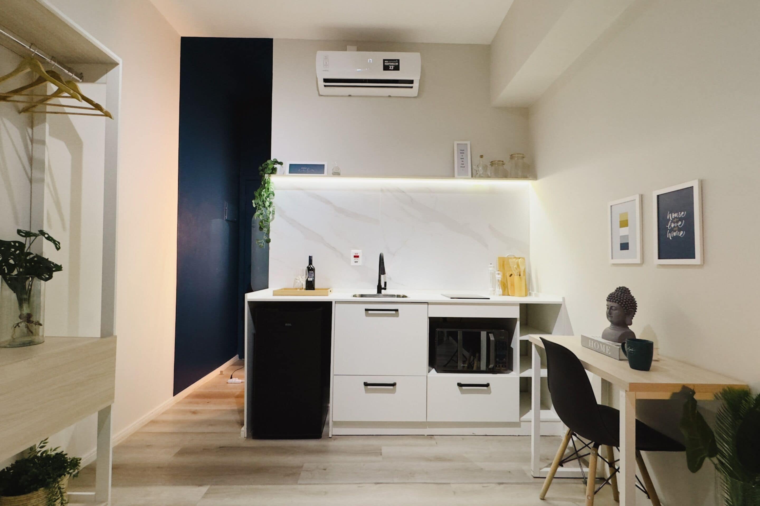 A compact kitchen with a built-in refrigerator, a sink, and a small dining area with a chair and table.