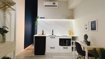 A compact kitchen with a built-in refrigerator, a sink, and a small dining area with a chair and table.