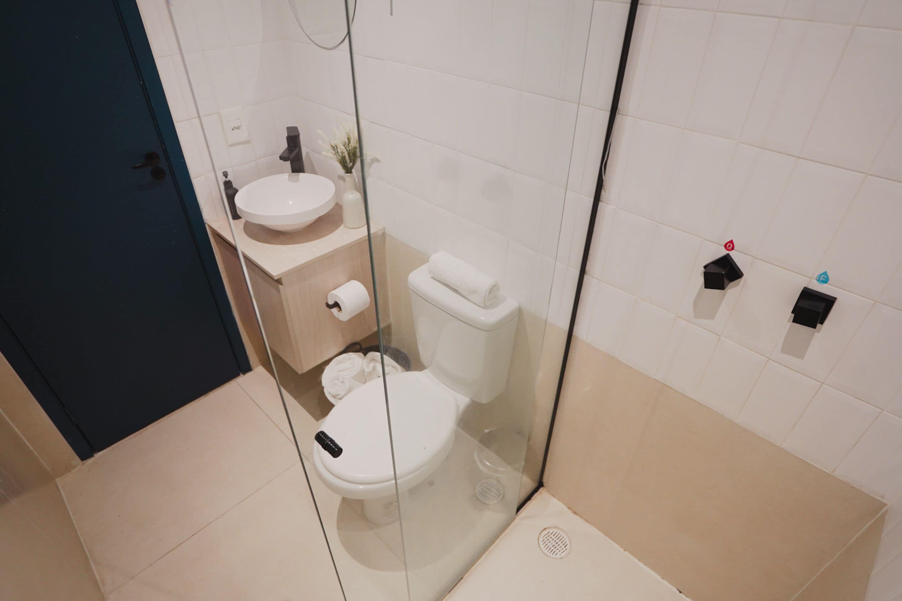 A modern bathroom with a glass-enclosed shower, a white sink, and a toilet.