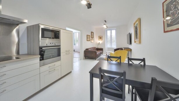 A modern kitchen with built-in appliances, a dining area with a table and chairs, and a living space with a sofa and a coffee table. - Appartment the House of Hera (Vierzon)