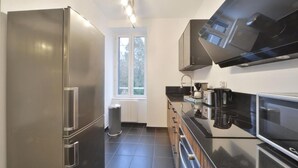 Een moderne keuken met roestvrijstalen apparatuur, een raam en een zwart aanrecht.