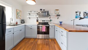 Een moderne keuken met roestvrijstalen apparatuur, lichtblauwe kastjes en een houten aanrecht.