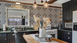 Una cocina moderna con armarios oscuros, un ventanal grande y un jarrón decorativo en la isla.