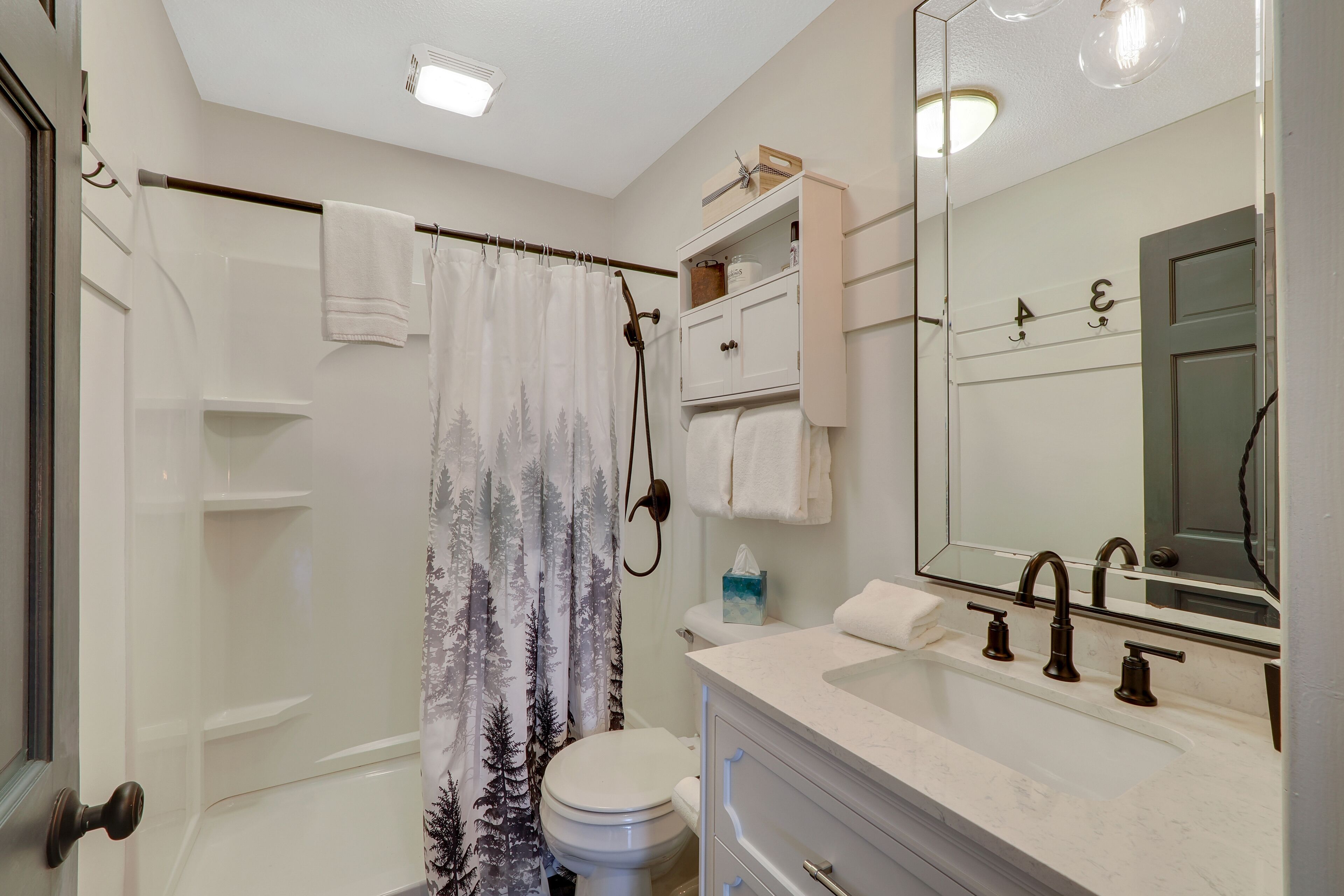 A bathroom with a shower, toilet, and sink.