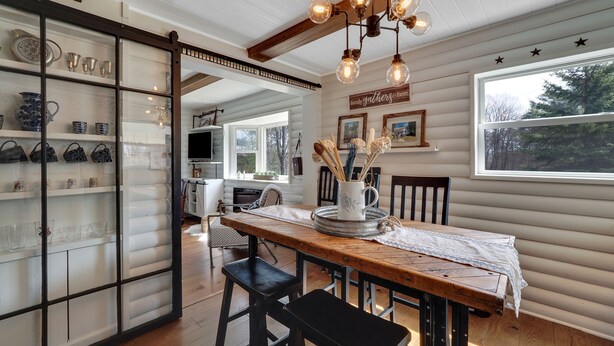Un comedor con una mesa de madera, sillas negras y una lámpara decorativa.