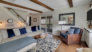 Una habitación acogedora con un sofá blanco, un sillón de cuero marrón y una alfombra estampada.