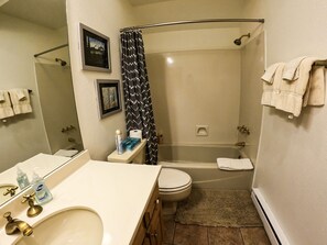A bathroom with a bathtub, toilet, sink, and a shower curtain. - 2 Miles North of Purgatory! Heated Pool ! (Durango)
