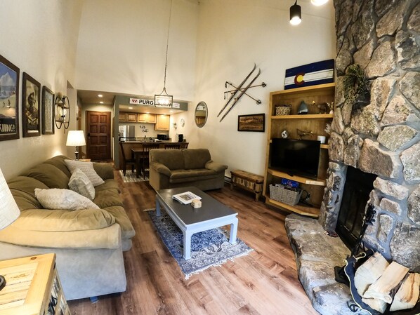 A cozy living room with a stone fireplace, a kitchen in the background, and a dining area. - 2 Miles North of Purgatory! Heated Pool ! (Durango)