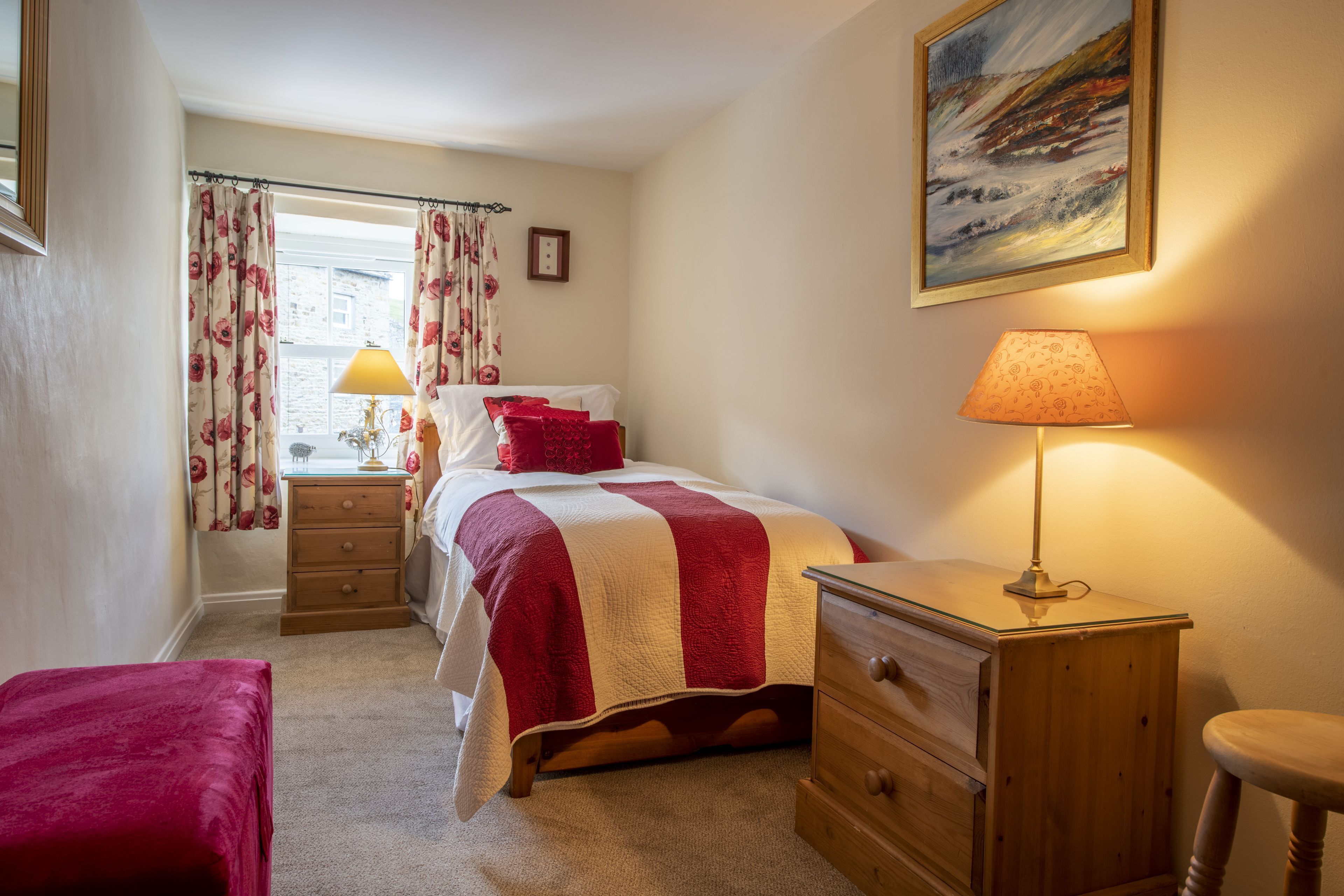 Une chambre à coucher comprenant un lit, une table de chevet, une commode, une chaise et une fenêtre avec des rideaux.