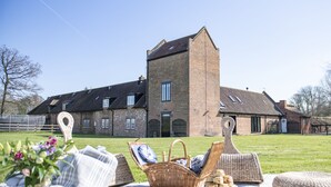 Ein Picknick mit Korb, Decke und Lebensmitteln vor einem Backsteinhaus mit einem Turm.