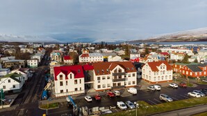 A town with a mix of residential and commercial buildings, a main road, and a parking lot with several cars. - Hrimland - Luxury Apartment for 2 persons (Akureyri)