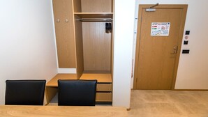 A room with a wooden wardrobe, a small table with chairs, and a door with a fire safety sign. - Hrimland - Luxury Apartment for 2 persons (Akureyri)