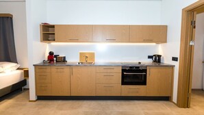 A modern kitchen with wooden cabinets, a built-in oven, and a coffee maker. - Hrimland - Luxury Apartment for 2 persons (Akureyri)
