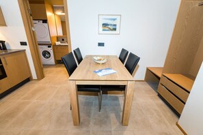 Una cocina compacta con lavadora, una mesa de comedor con sillas y un pequeño banco.