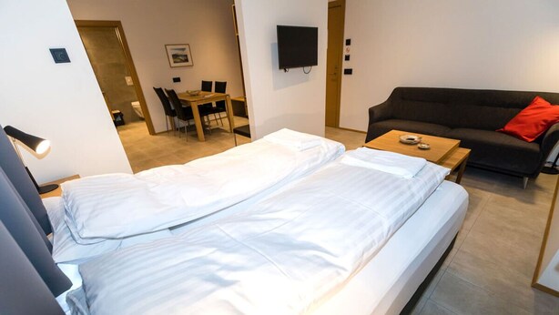 A hotel room with two beds, a sofa, a TV, and a dining area. - Hrimland - Luxury Apartment for 2 persons (Akureyri)