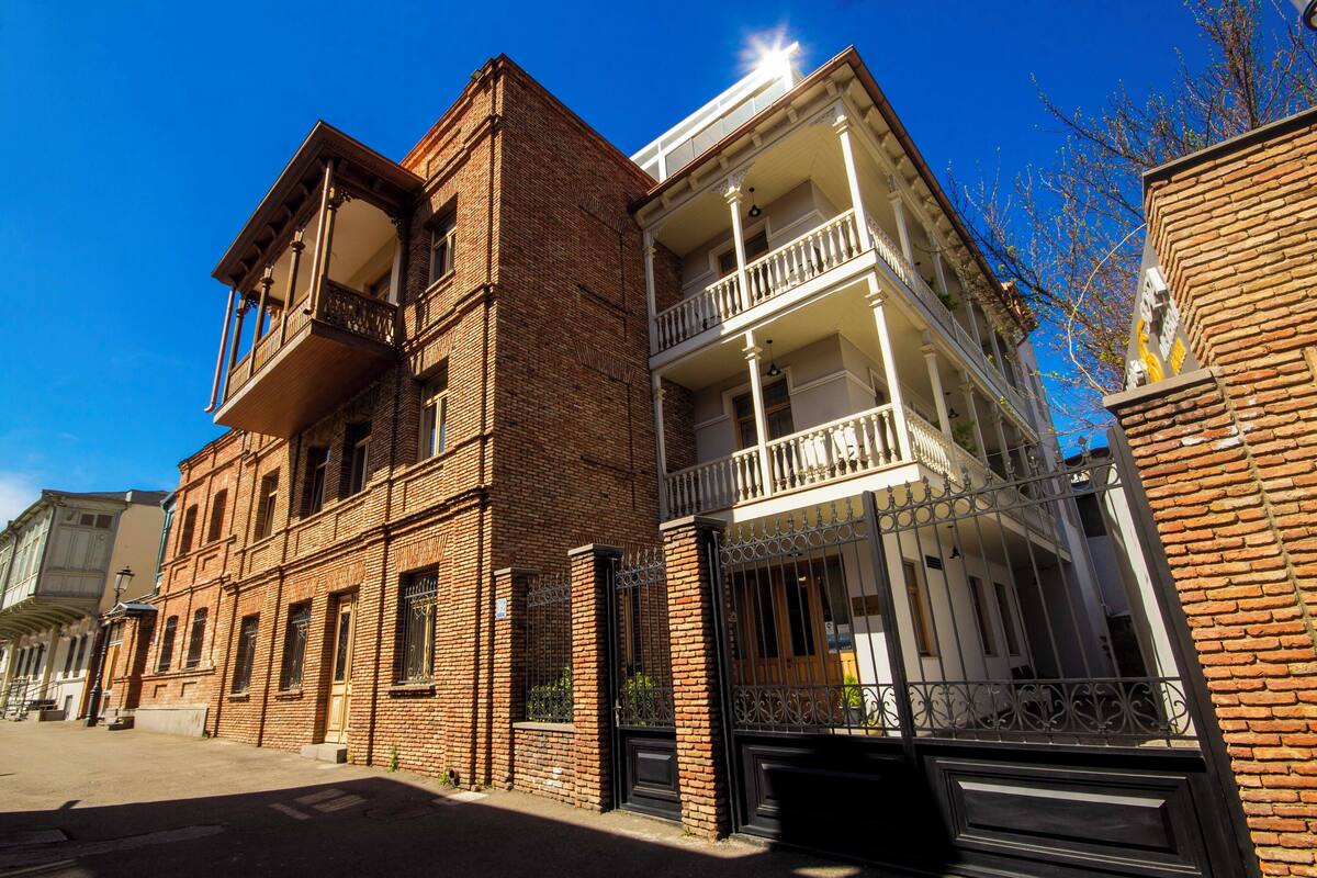 A multi-story building with a brick facade, balconies, and a gated entrance.
