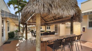 An outdoor dining area with a thatched roof, wooden tables, and chairs. - Expo Motel (Hollywood)