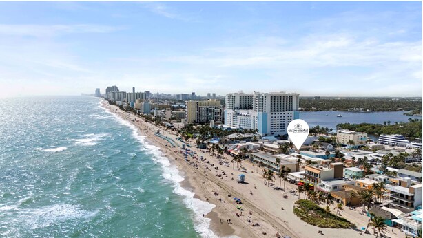 A coastal cityscape with a beachfront hotel, palm trees, and a clear view of the ocean. - Expo Motel (Hollywood)